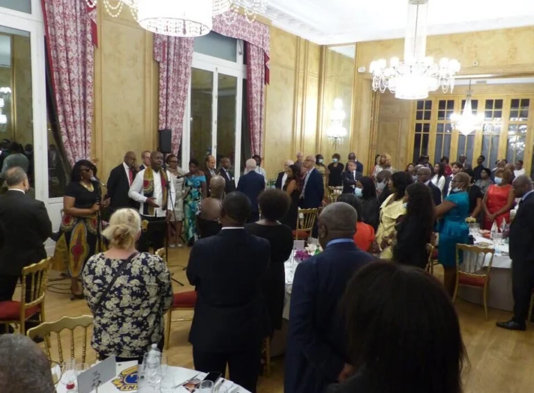 Jazz Pearl's, soirée de gala avec un chanteur et une chanteuse s’adressant à un public debout, dans une salle élégante ornée de lustres.