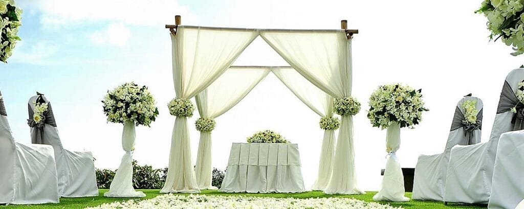 Décoration élégante d'une cérémonie de mariage en extérieur, avec arche florale et allée fleurie.